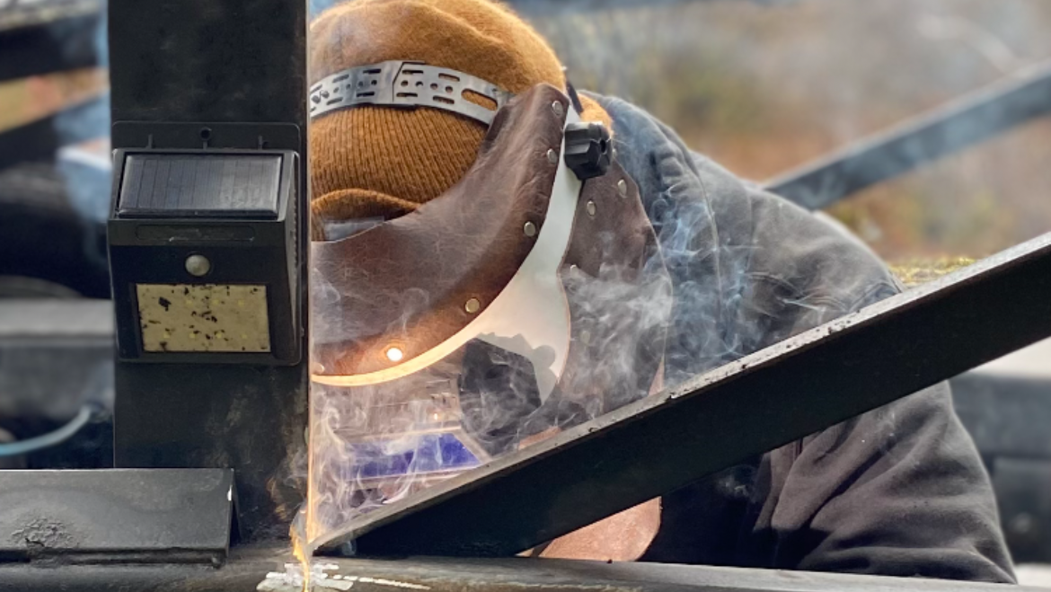 Mayes welder mid-arc on steel, sparks and smoke