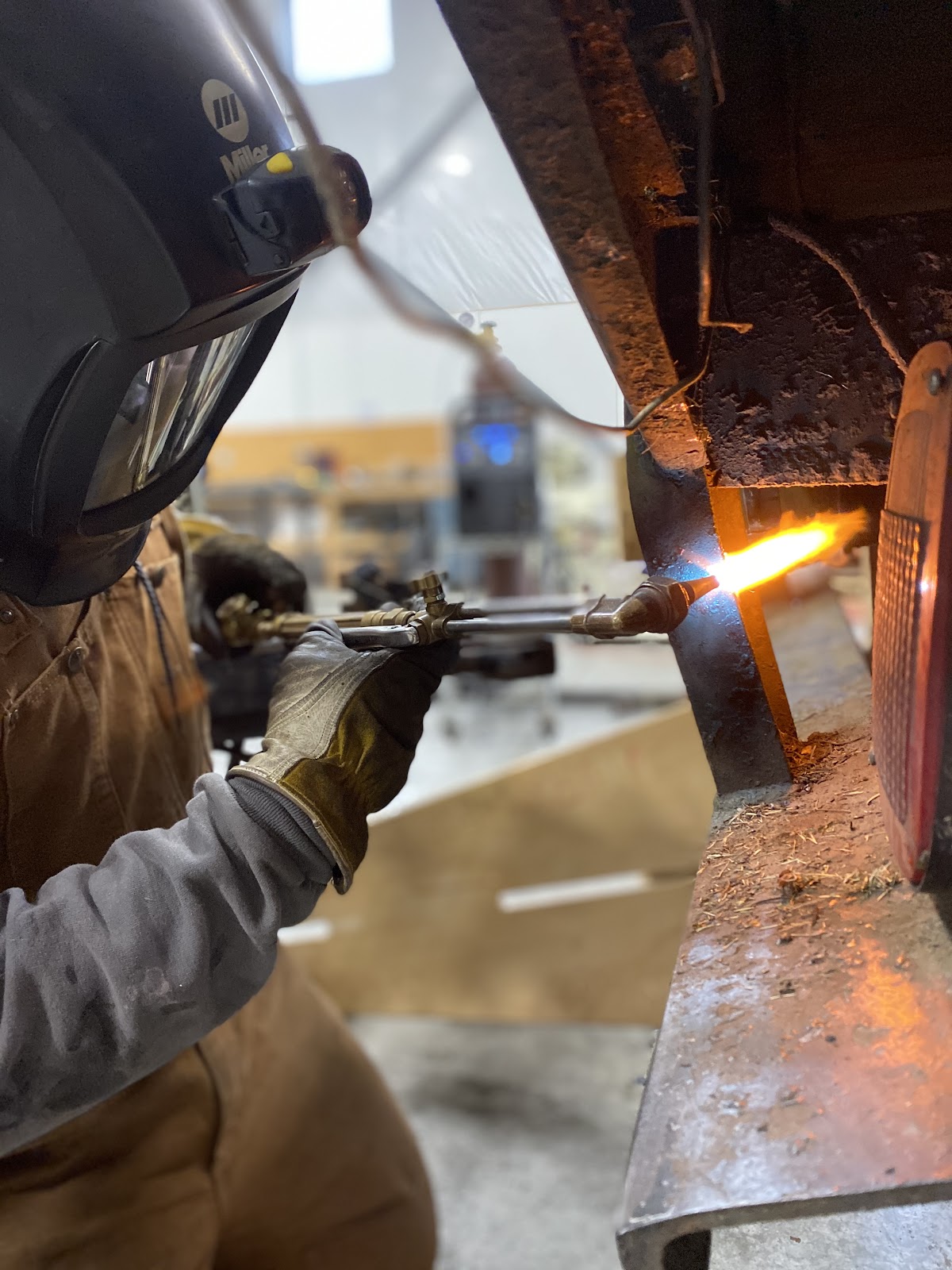 Welder oxy-torch cutting a trailer underframe, molten glow